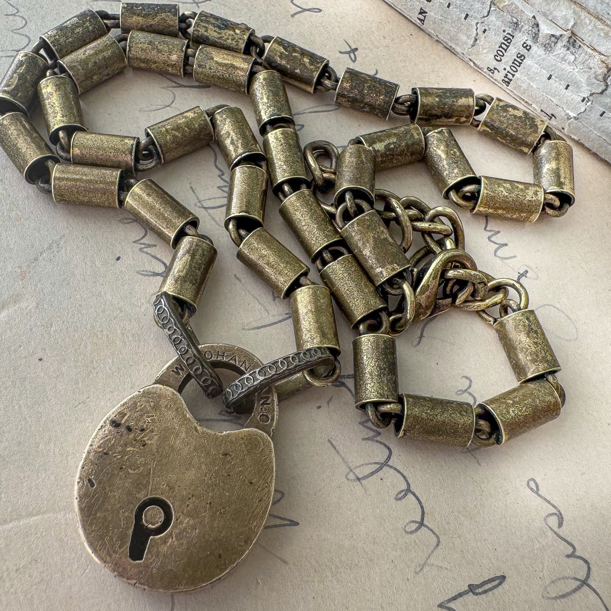 Bronze padlock necklace on a textured surface