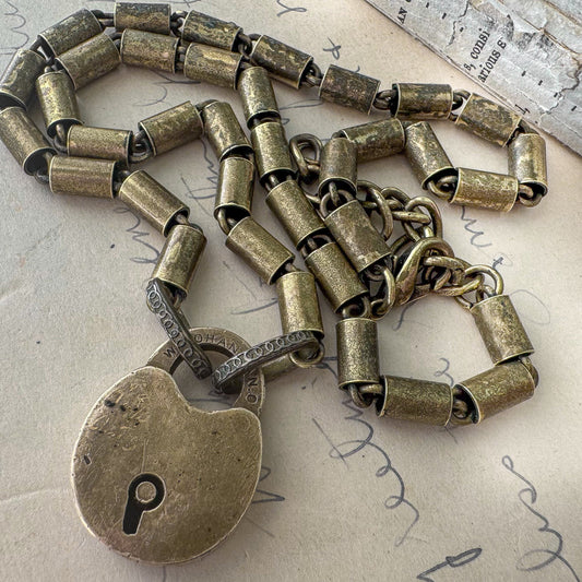 Bronze padlock necklace on a textured surface